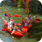 Picture of two tandem kayaks each with two people in them sporting pride gear
